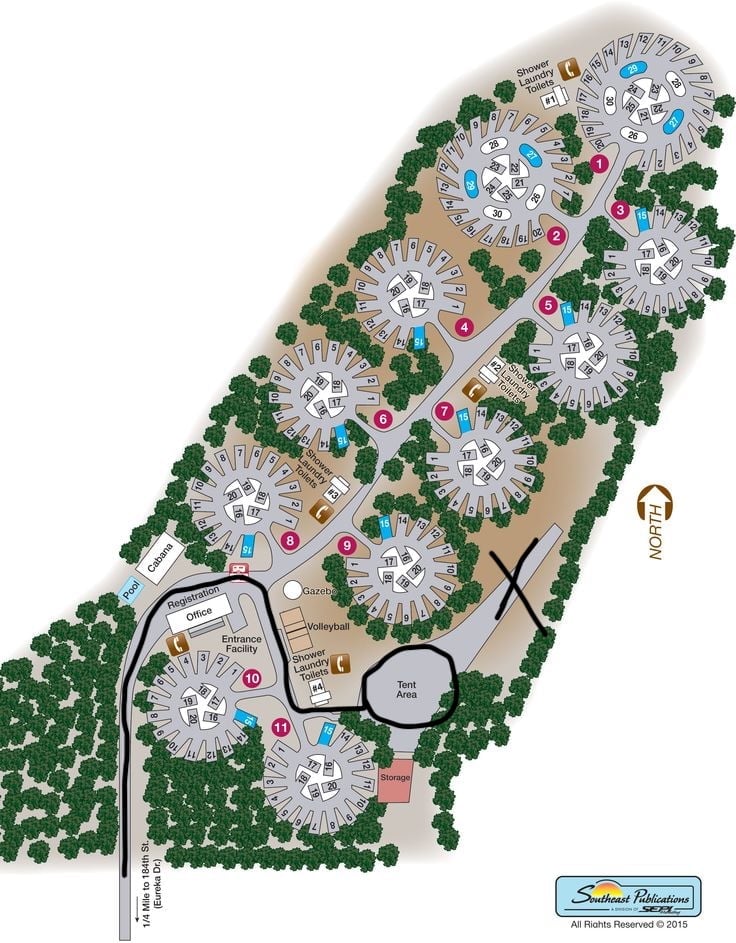Overhead site plan of a residential community with circular buildings, green landscaping, roads, and amenity areas